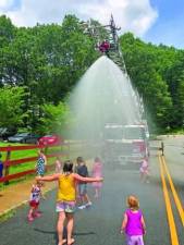 Children cool off in the spray from a firetruck hose during Stanhope Family Fun Day last year. (File photo by Greg Smith)