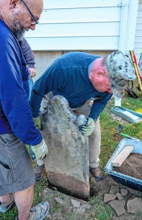 Pete Dresso and Peter Litchfield replace a grave marker.