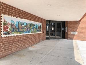 A mini-version of the mural on Moran Street hangs outside the Newton municipal building entrance. (Photo by Kathy Shwiff)