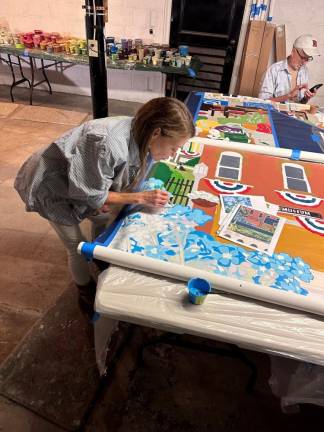 Local floral designer/artist Eileen Ibranyi paints flowers on the mural. (Photo provided)