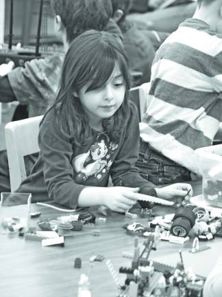 Abigail Biederman, 5, of Newton looks for bits and pieces to complete her project.