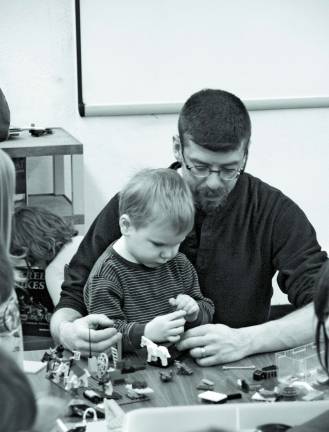 Matt, 3, and his father Timothy McQueen work together during the Lego club meeting Saturday.