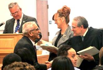 Orange County Court Judge Craig Brown welcomes a new citizen at Wednesday’s naturalization ceremony at the Government Center. In the background is County Clerk Kelly Eskew. At the podium is Deputy County Clerk James McGee.