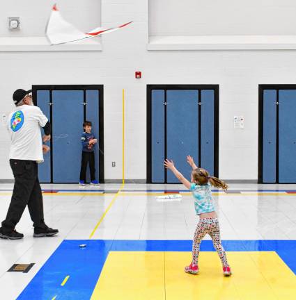 McKenna Reid reaches toward a kite being flown Saturday, March 1 in the Byram Lakes School cafeteria. Experienced indoor kite flyers taught those attending a kite building workshop how to fly kites indoors.