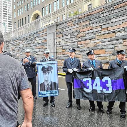 Members of the New York City Fire Department hold a picture of Stephen Siller and his engine number at the race.