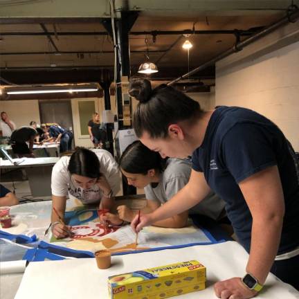 From left, Natalie Fung, Jennifer Ellsworth and Lauren Hennighan paint a section of the mural.