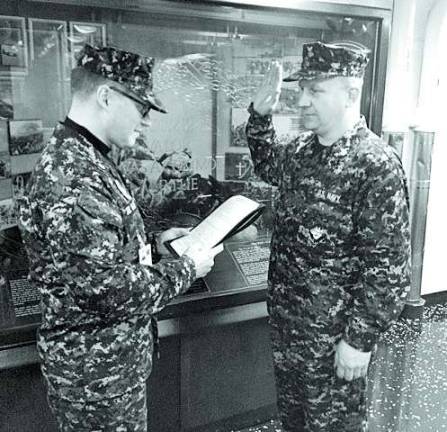 Photo Provided Commanding Officer Adrian DelValle administers the oath to MA1 Mitchell Ellicott as he re-enlists in the US Navy Reserve for another two years.