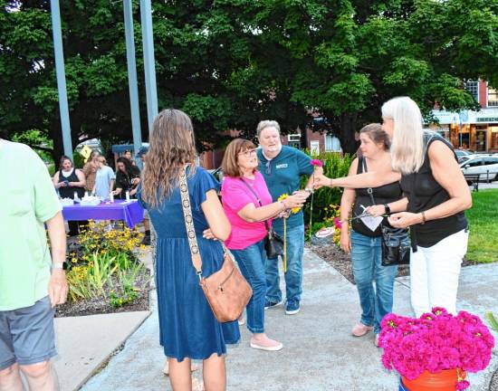 Flowers are handed to those attending the Candlelight Vigil and Walk through Remembrance Display sponsored by the Sussex County Recovery Community Center.