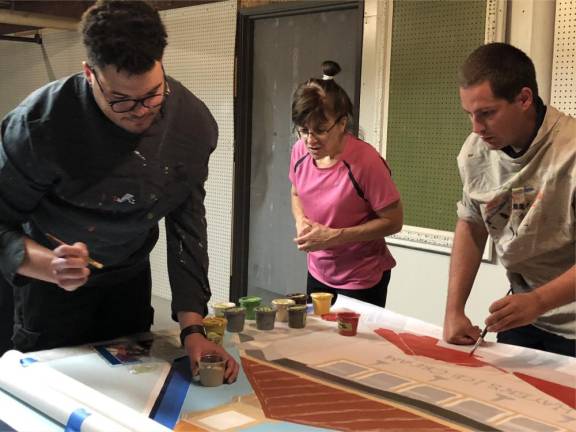 From left, Newton First Aid Squad members Will Taylor, Kathy Posey and John-Paul Couce help paint the mural that will be placed at Moran and Spring streets this fall.