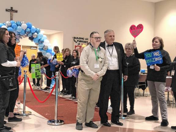 <b>Volunteers welcome a guest and his buddy walking the red carpet into the prom.</b>