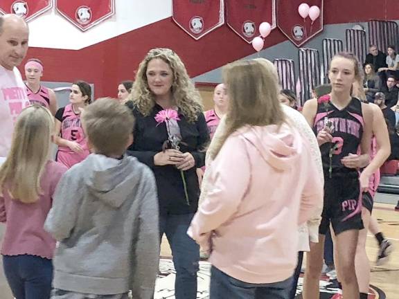 Players hand flowers to cancer survivors and those with cancer during a break in the game.