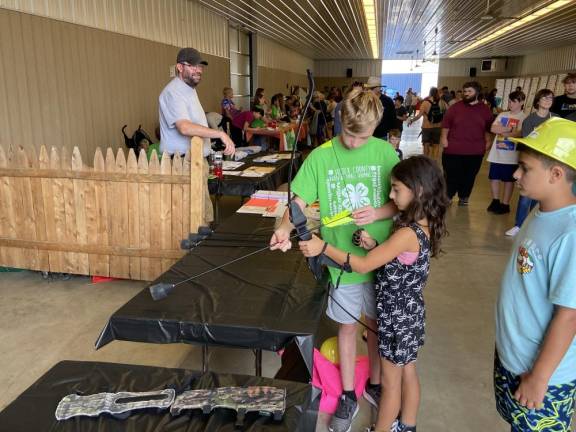 Joseph Cosh, 12, of Wantage, a member of the Aim to Survive 4-H Club, teaches Layla Abedrabbo, 9, of Vernon how to shoot an arrow.