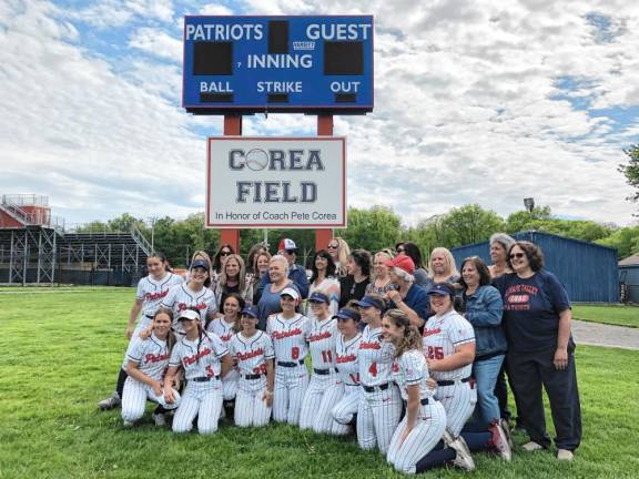 Current and former softball players pose under the new sign.