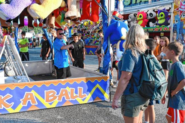 <b>Fair-goers listen to a pitch to play a game. (Photo by Maria Kovic)</b>