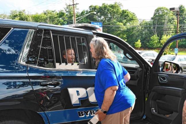 A boy checks out the inside of a police car.