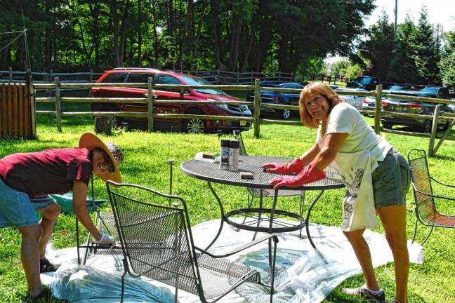 <b>Dora Torres of Jefferson and Elisa Young of Oak Ridge paint a table and chairs.</b>