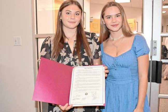 Magdalen Costello, left, a sophomore at Pope John XXIII Regional High School, and her sister Olivia, both of Green Township, hold a proclamation from the Sussex County Board of County Commissioners recognizing their work with the Weekend Bag program. (Photo by Maria Kovic)