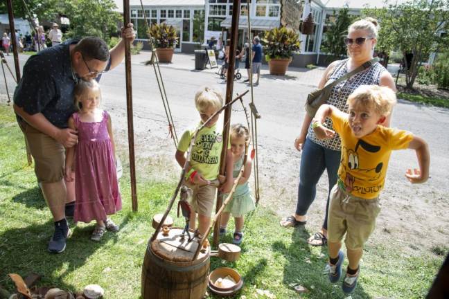 FR22 The Broesder family of Hampton Township watches the wooden doll dancing at the tent of woodworker and bowl turner Roger Abrahamson on Sunday, Aug. 6. He was controlling the puppet with his hand while he played the banjo. Asher, 6, at right, dances along with the song, which said when to jump. From left are Kyle; Eden, 6; Judah, 6; Marley, 2; and Marisa. (Photo by John Hester)