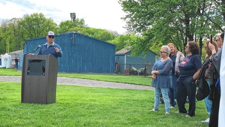 Former softball coach Pete Corea speaks at the ceremony. At right are his former players.