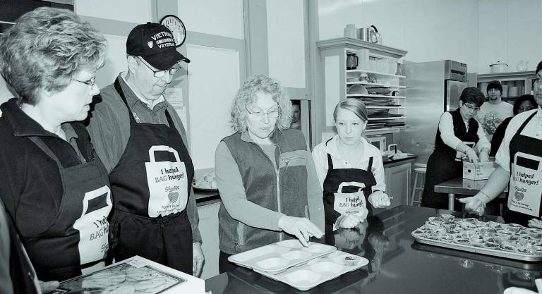 Laura Lippencott (center) gives instructions to ShopRite volunteers (left to right) Cherie Hudson, Larry Leve, Michelle D&#146;Onofrio and Shaun Estores while Cathie Miller and Bev Ruddock work in the rear of the kitchen at Manna House in Newton.