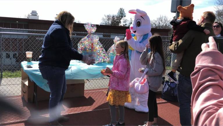 Mayor Michelle Teets, left, presents big Easter baskets to the five children who found golden eggs.