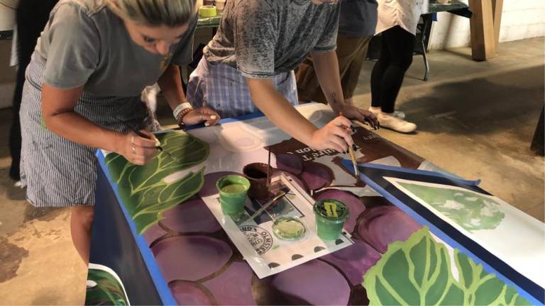 Stephanie Schick of Newton and her daughter Faith, 19, help paint the mural Sunday, July 30.